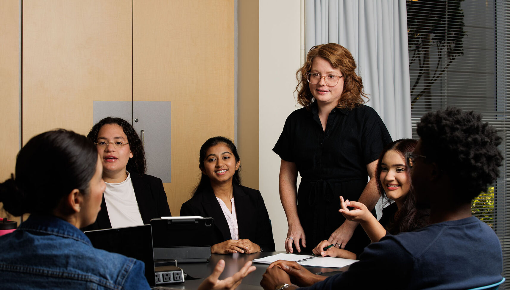 A teacher lectures to a small group of students in a conference room