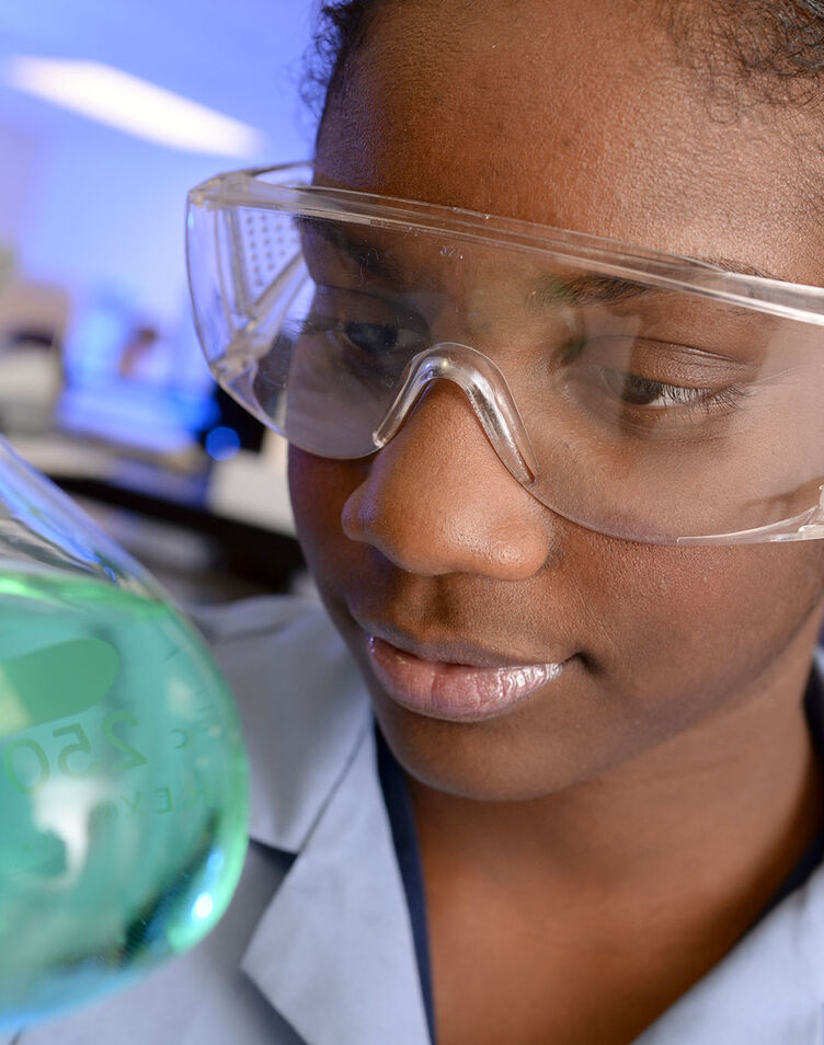 A female student observes a beaker in the chemistry lab